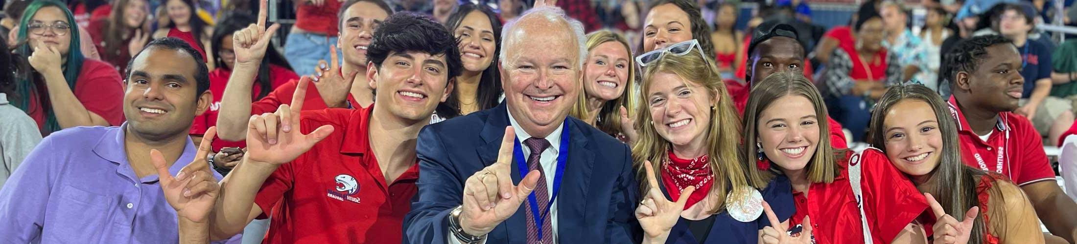 President Bonner holding up J sign with a group of students.